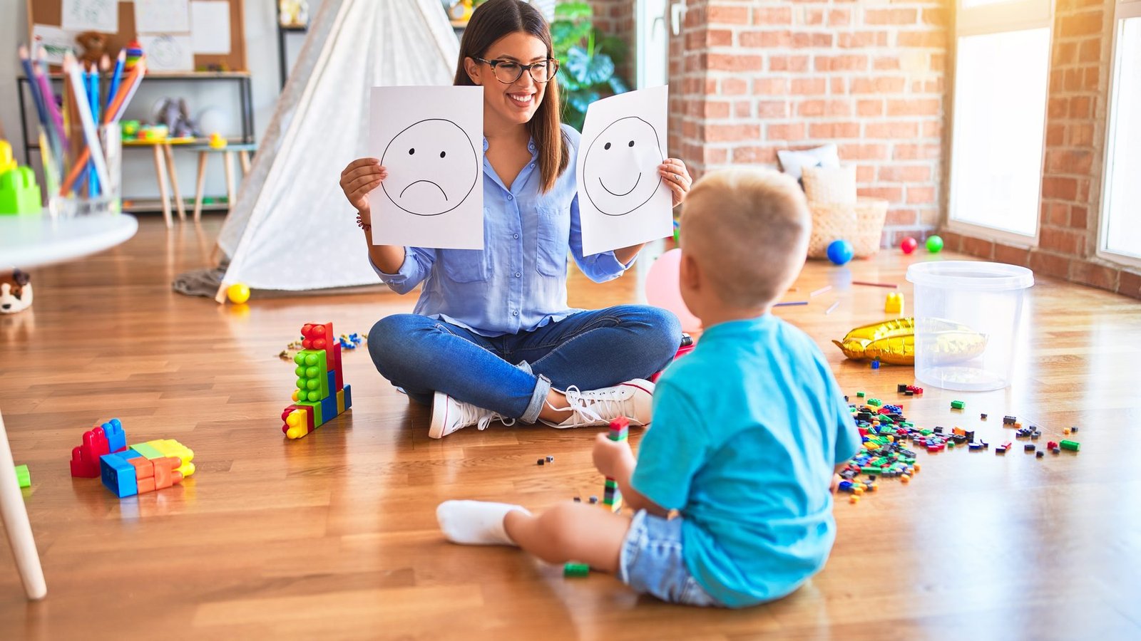A therapist and a young child playing together on the floor during a session